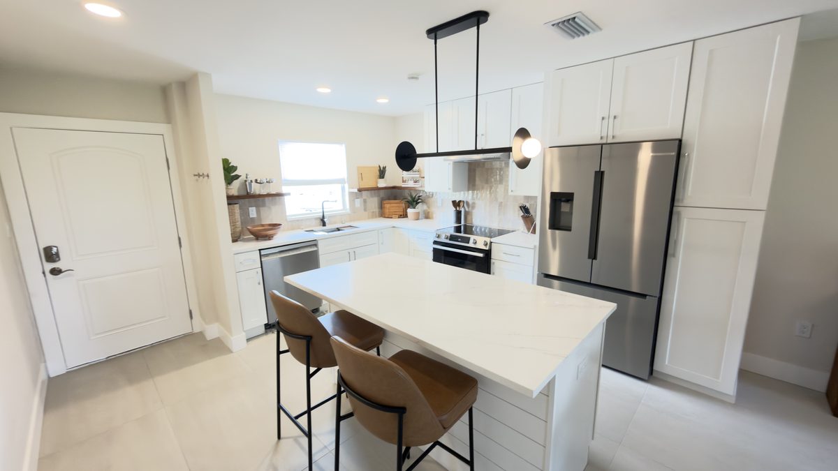 Condo kitchen remodel with white cabinets and quartz island seating