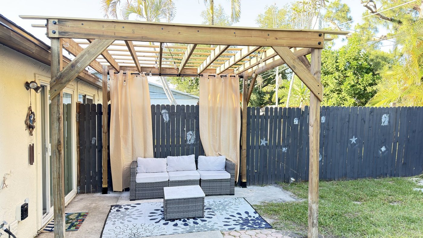 Pergola with outdoor curtains and lounge seating in a private backyard